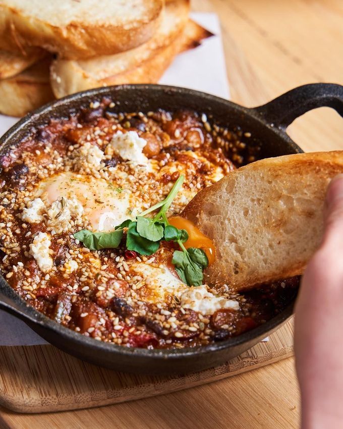 A skillet of baked eggs in tomato sauce with chorizo, chickpeas and Persian fetta