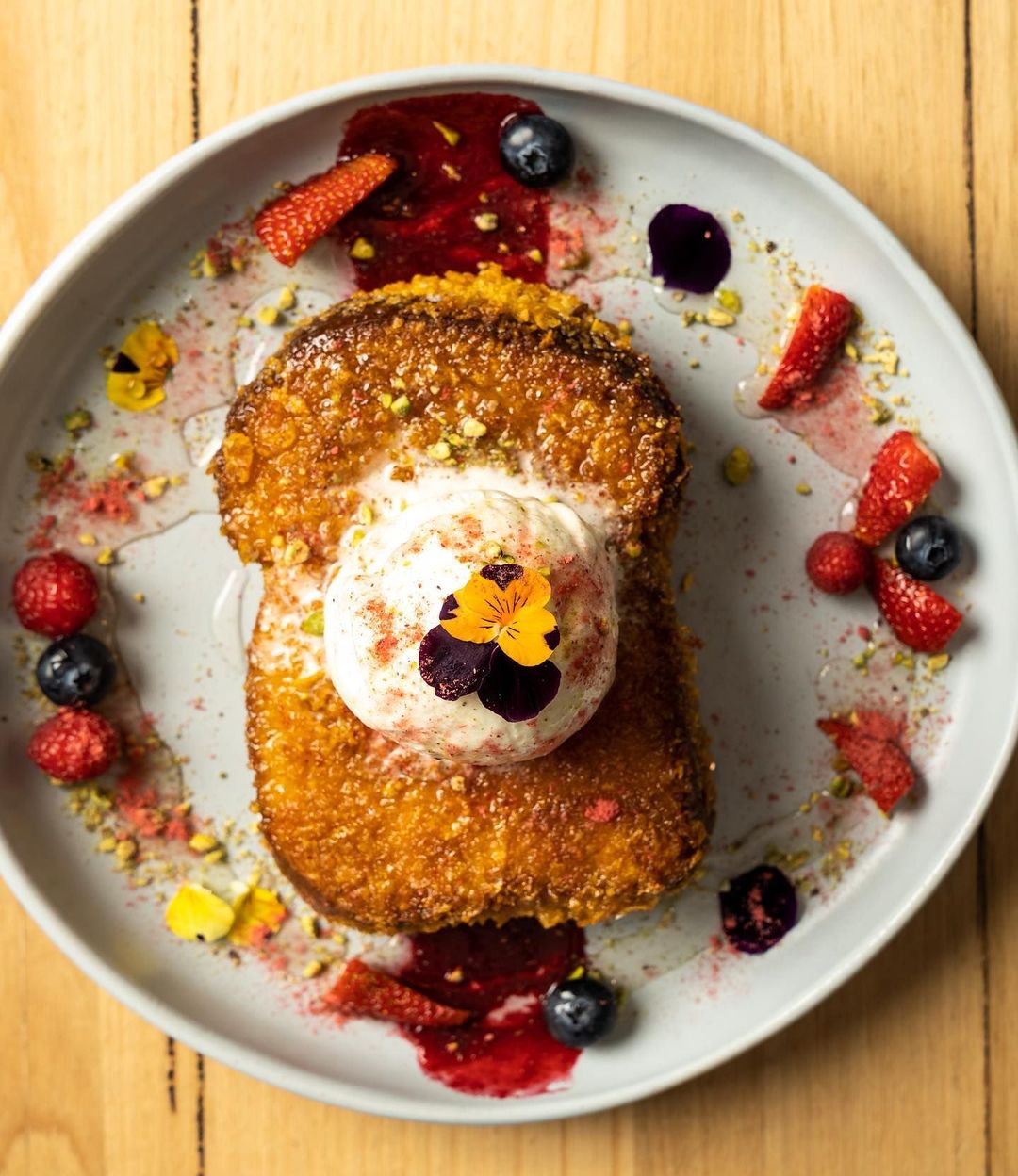 Crumbed French toast plated with fruit and a dusting of icing sugar