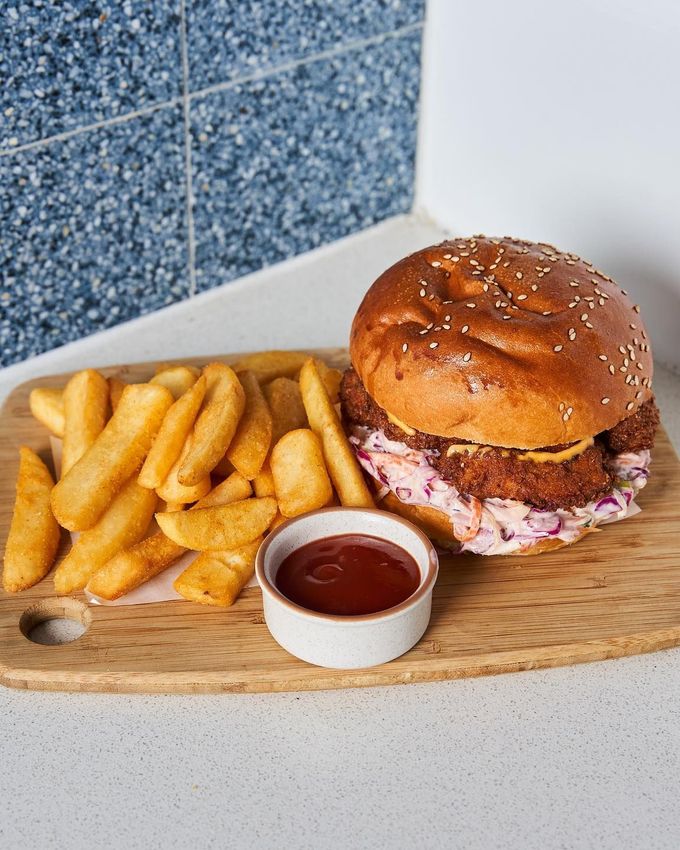 Crispy chicken burger with apple slaw and sriracha aioli, served with a side of chips