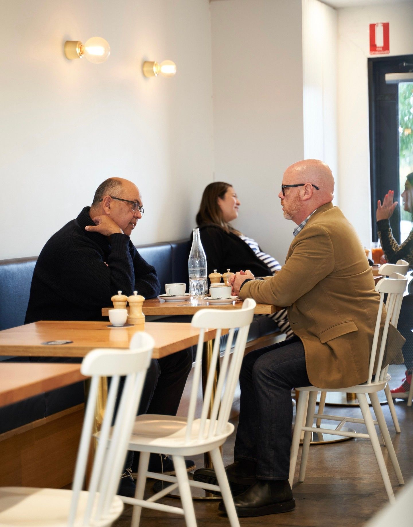Customers deep in conversation over coffee at a wooden table inside Drip Cafe