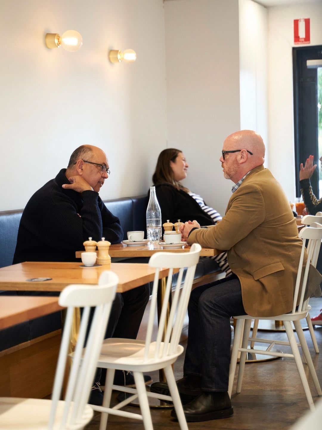 Customers deep in conversation over coffee at a wooden table inside Drip Cafe