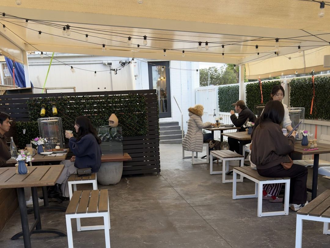 Drip Cafe's covered outdoor courtyard with timber tables, benches and string lights