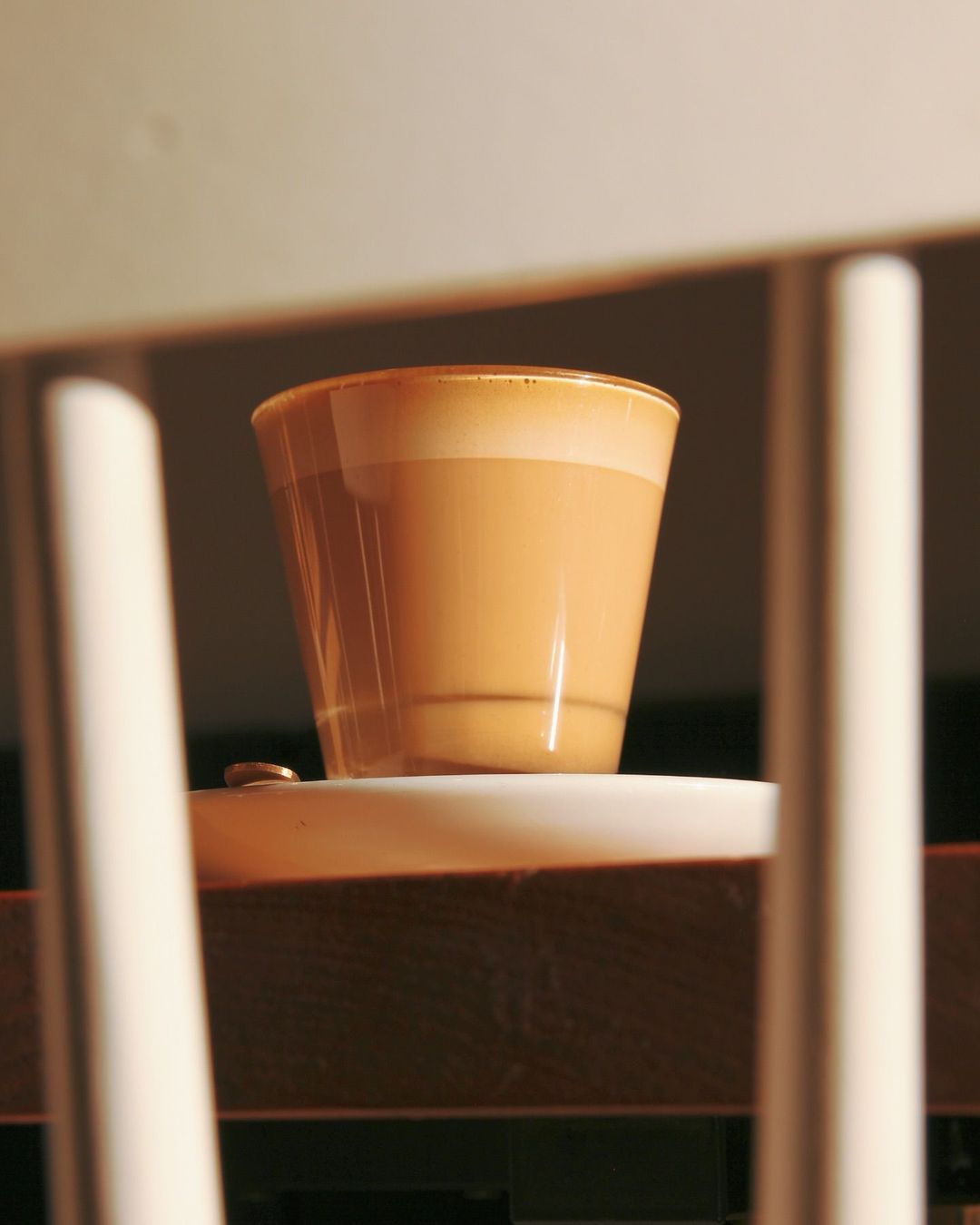 A latte in a glass tumbler catching late morning light through the window
