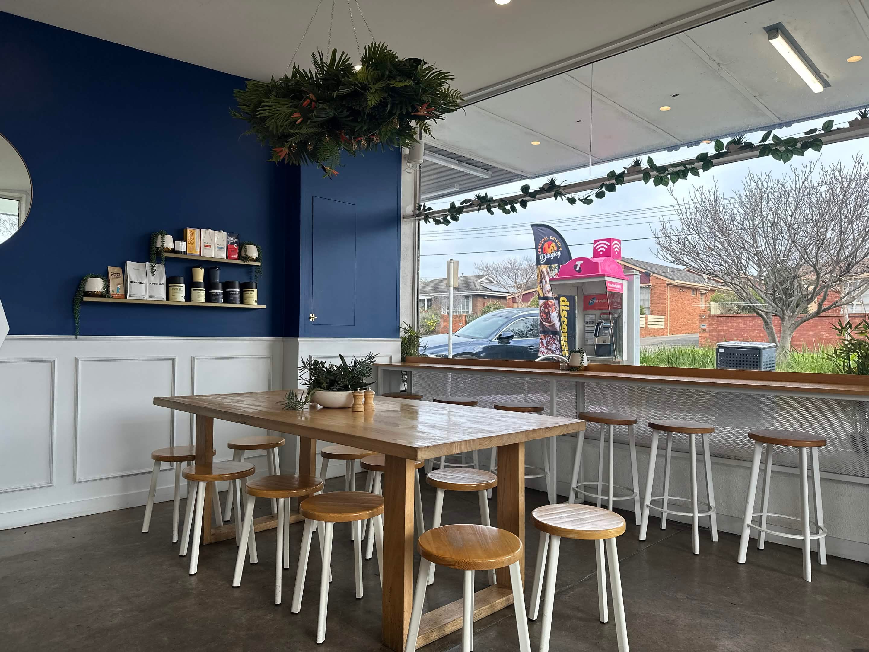 Drip Cafe interior. Azure blue walls, white wainscoting and timber stools by the corner window in Cheltenham