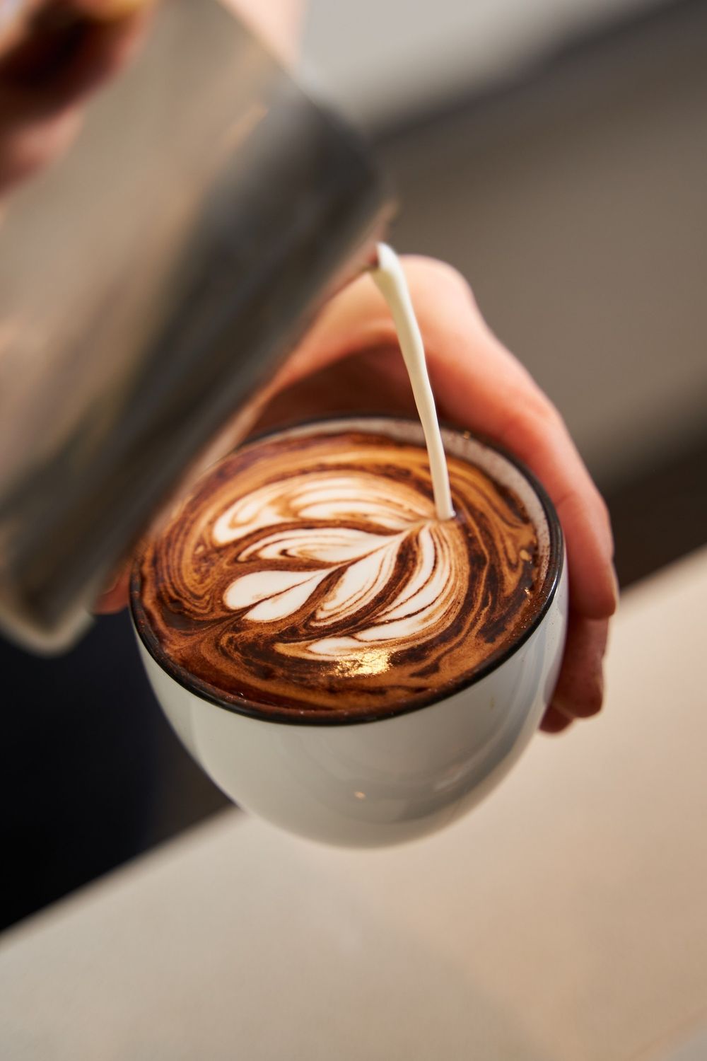 A barista pouring milk into a cup of espresso