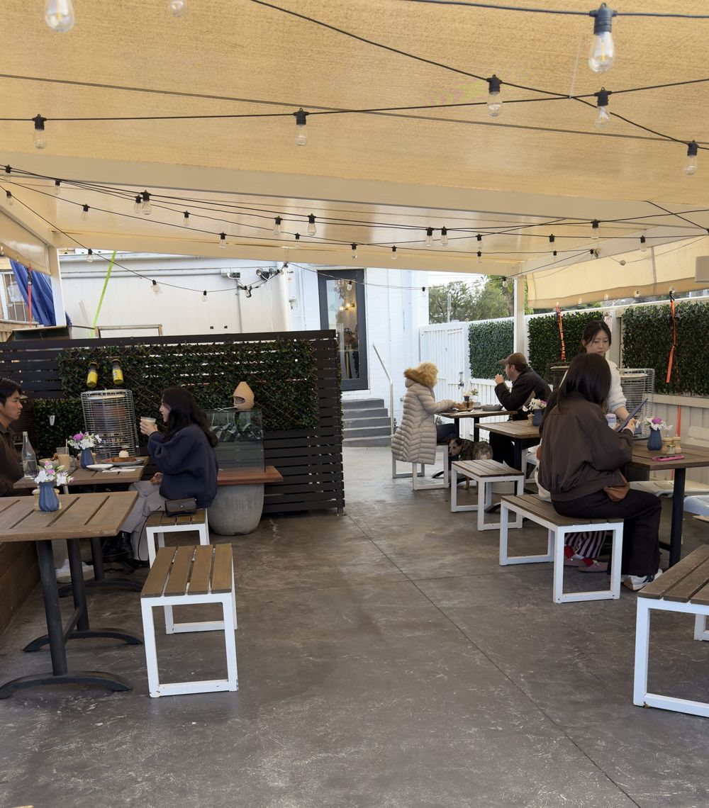 Guests eating in the courtyard, screened by hedging and dark timber slats
