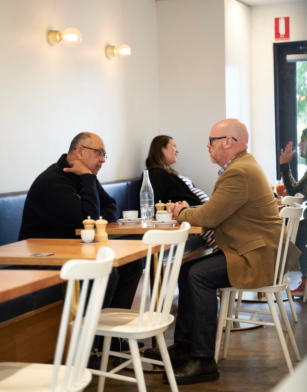 Guests seated at timber tables in Drip's blue dining room