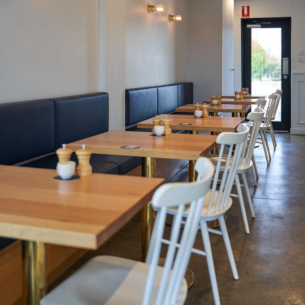 The dining room laid for service, tables set along the banquette